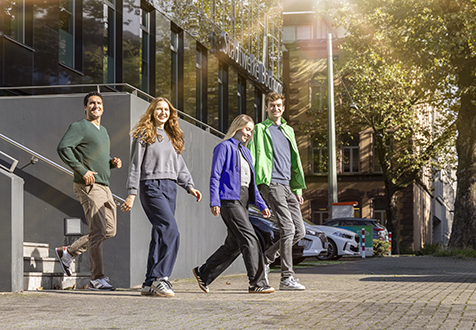 Vier junge Menschen laufen vor einem Gebäude in Bochum